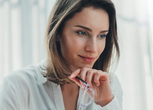Woman with under eye bags holding her glasses