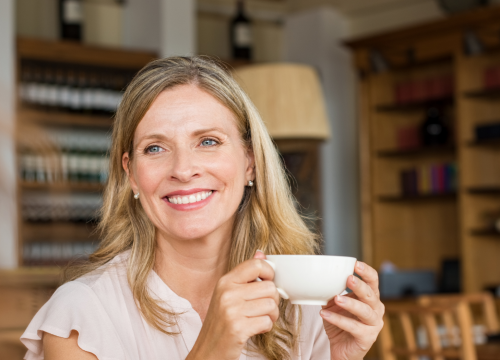 Older woman holding a coffee cup at a cafe