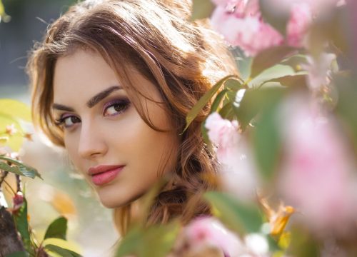 Woman surrounded by green and flowers in spring