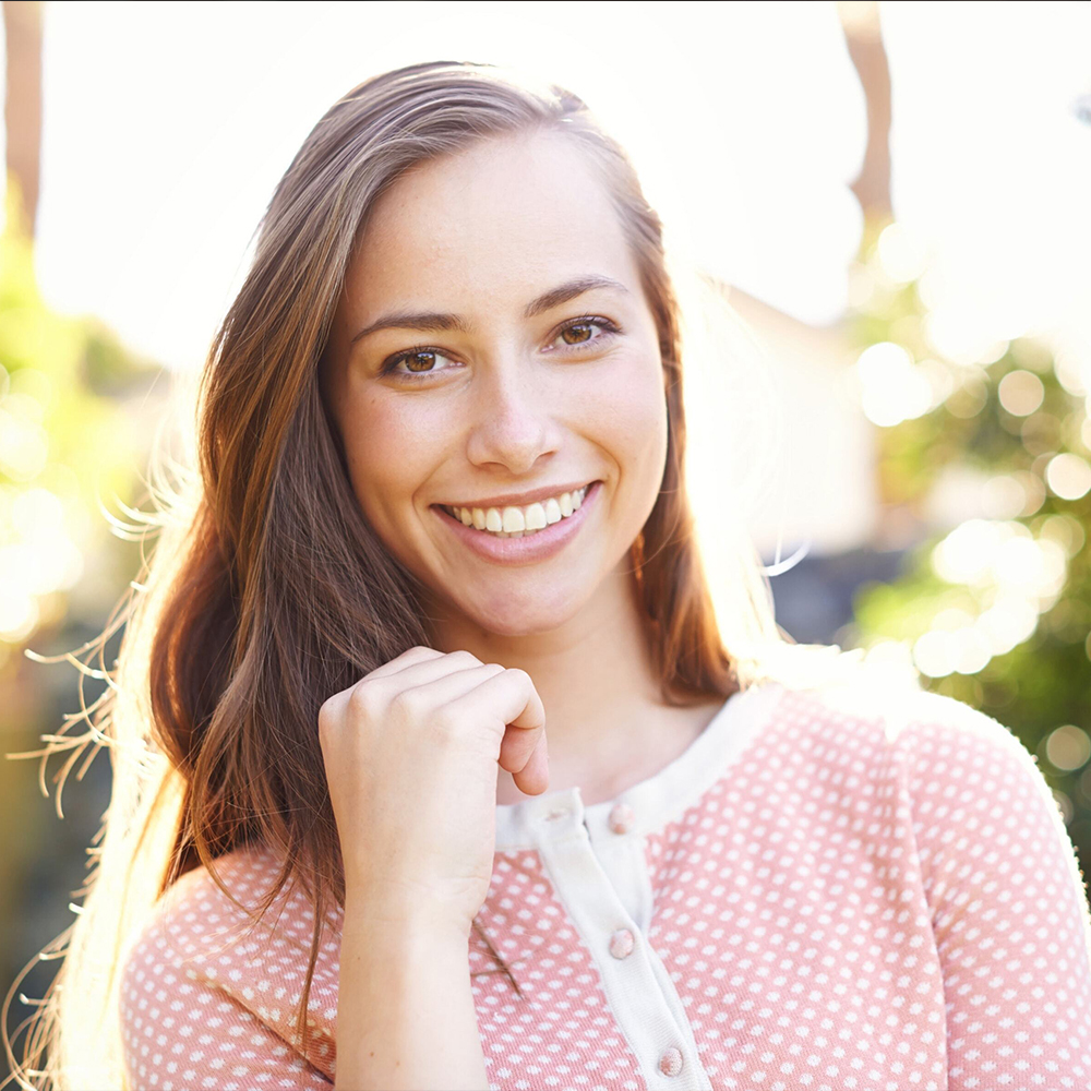 Smiling brunette woman with great skin wearing a pink shirt